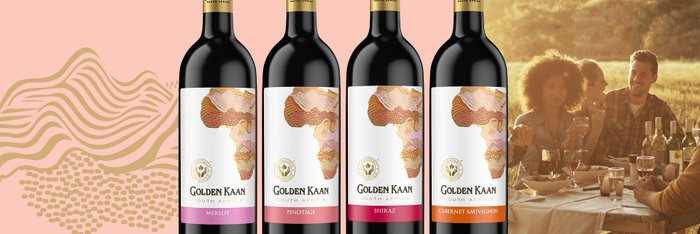 Vier Flaschen Golden Kaan Wein stehen vor einer fröhlichen Gruppe von Freunden, die im Freien zusammen essen und trinken.